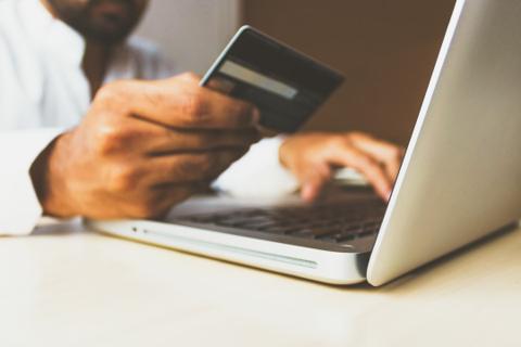 person holding credit card while using a laptop for online business transactions