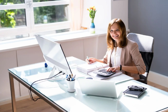 Woman working at laptop with notebook – fractional CFO services for eCommerce businesses including cash flow forecasting and inventory planning.